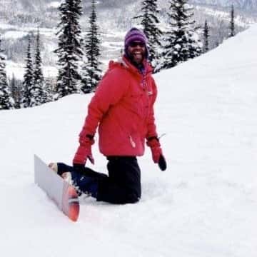 a person riding a snowboard down a snow covered slope